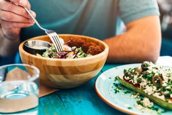Ein Mann isst Salat: Ob sich Fibromyalgie mithilfe einer speziellen Ernährung bessern kann, bleibt fraglich.