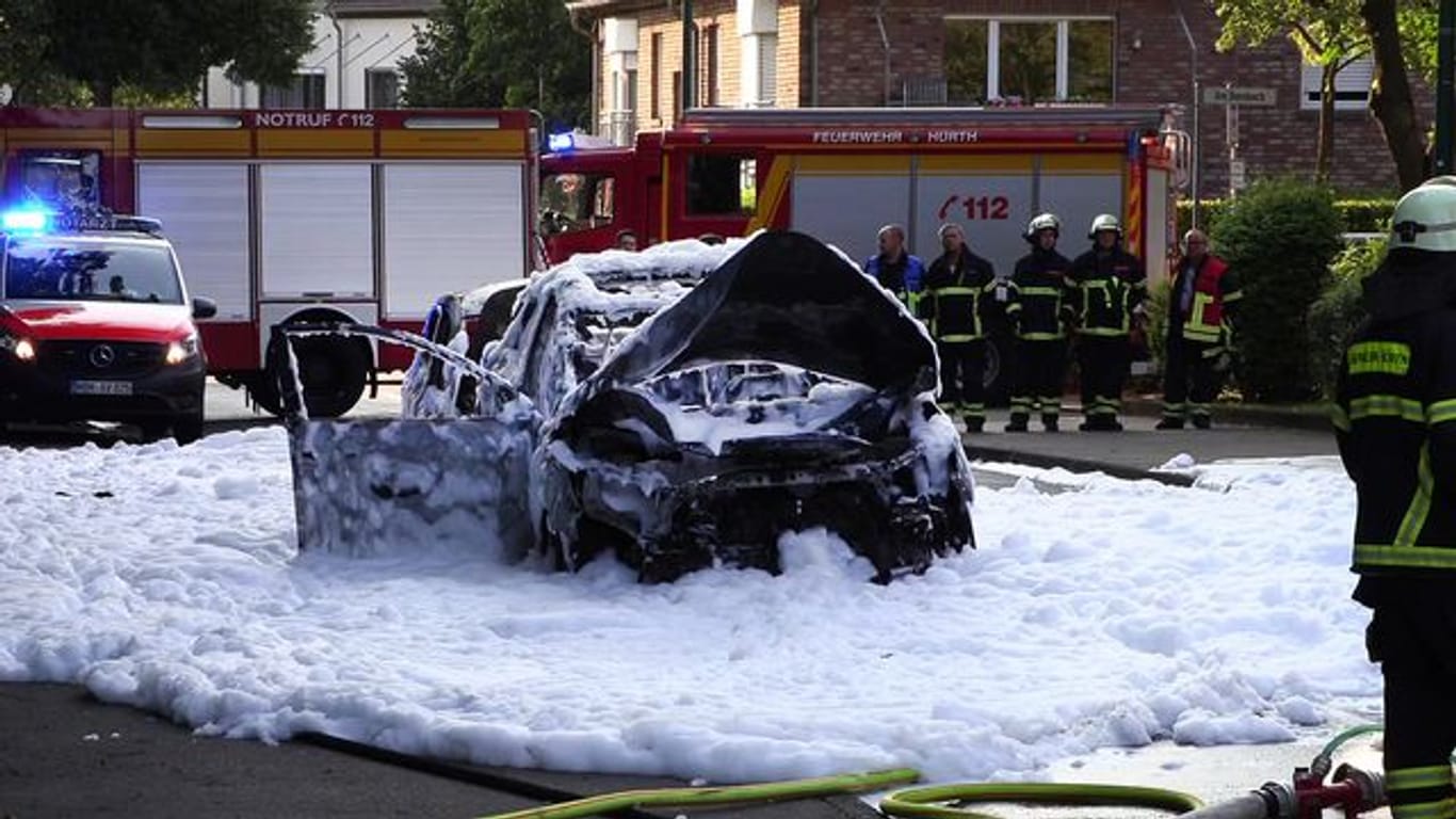 Auto-Explosion in Hürth: Das ausgebrannte Wrack des Fahrzeugs ist von Löschschaum bedeckt.