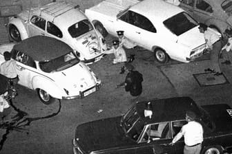 Bewaffnete Polizisten hinter den Autos (Archivbild): Die Beamten sind gegenüber der Deutschen Bank in Deckung gegangen.
