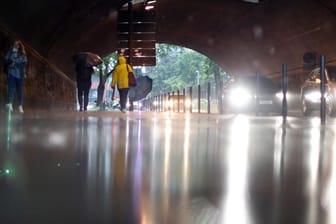Menschen laufen bei Regen durch eine Kölner Unterführung (Symbolbild): Am Dienstag werden teils heftige Regenschauer erwartet.