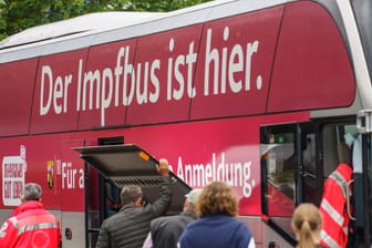 Ein Impfbus steht vor einem Aldi-Markt (Archivbild): Menschen warten in einer Schlange ohne vorherige Anmeldung auf ihre Corona-Impfung in Hechtsheim.