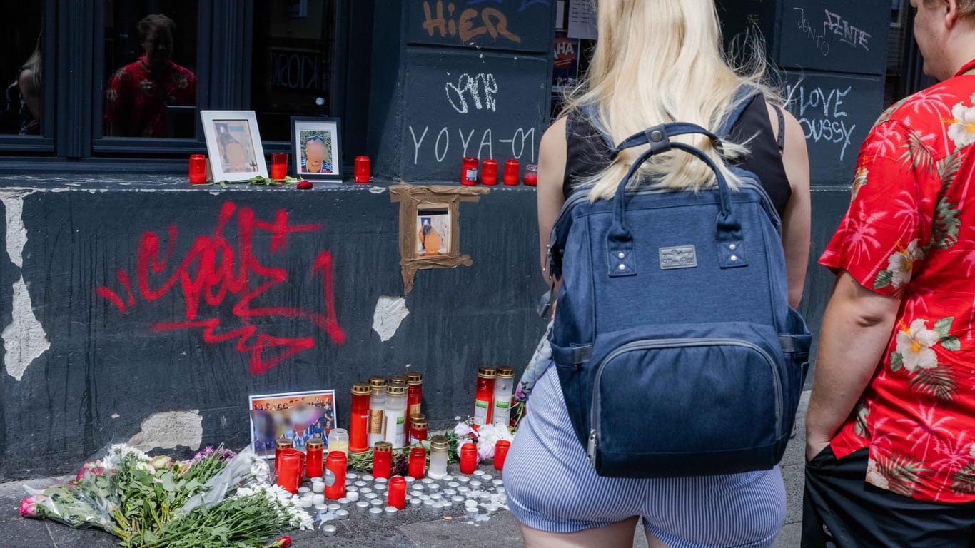 Menschen bleiben am Tatort stehen in der Zülpicher Straße stehen: An dem Gedenkort haben zahlreiche Bekannte und Freunde Blumen und Kerzen niedergelegt.