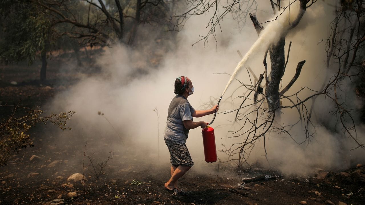 Eine Frau bekämpft mit einem Feuerlöscher einen Waldbrand im Dorf Cokertme.