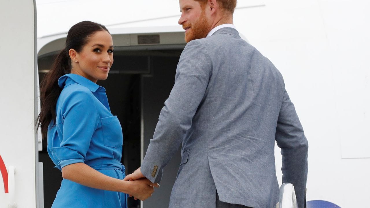 Prinz Harry und seine Frau Meghan besteigen ihr Flugzeug.