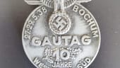 Eine Erinnerungsplakette für den Gautag 1938 in Bochum: Auch Orden und Ehrenzeichen wurden gefunden. Die Nazi-Objekte waren über 75 Jahre hinter einer Wand versteckt.