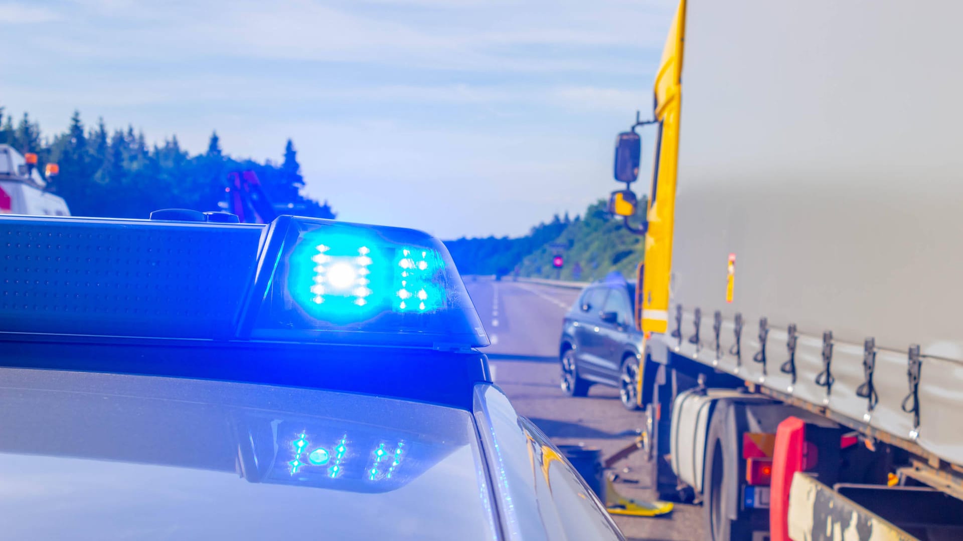 Ein Polizeiauto steht an einem Unfallort neben einem Lkw (Symbolbild): Bei dem Unfall wurden alle Insassen des Pkw verletzt. Ein Polizeiauto steht an einem Unfallort neben einem Lkw (Symbolbild): Bei dem Unfall wurden alle Insassen des Pkw verletzt.