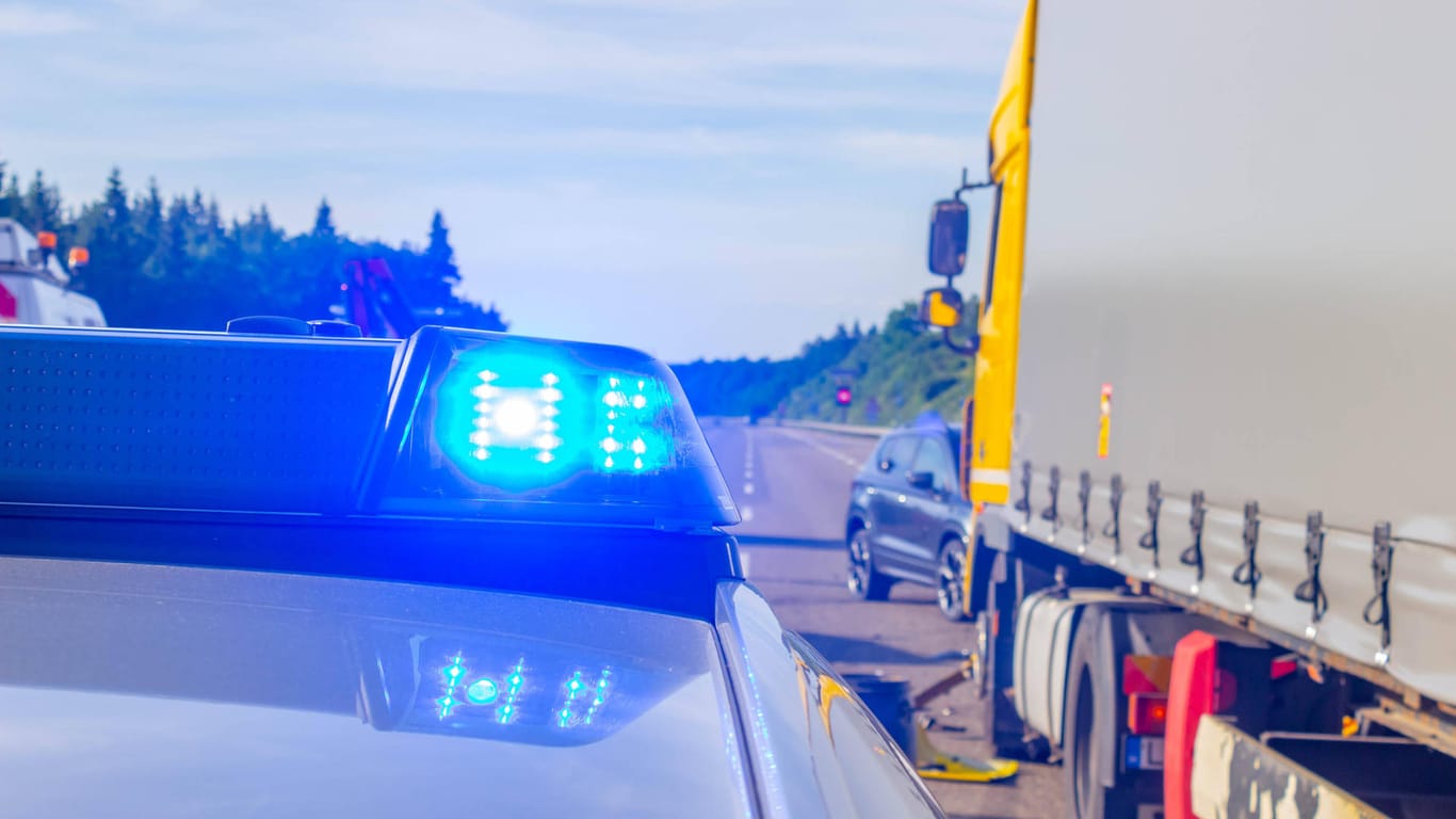Ein Polizeiauto steht an einer Unfallstelle neben einem Lkw (Symbolbild): An der Kollision auf der A1 waren drei Lkw und ein Pkw beteiligt.