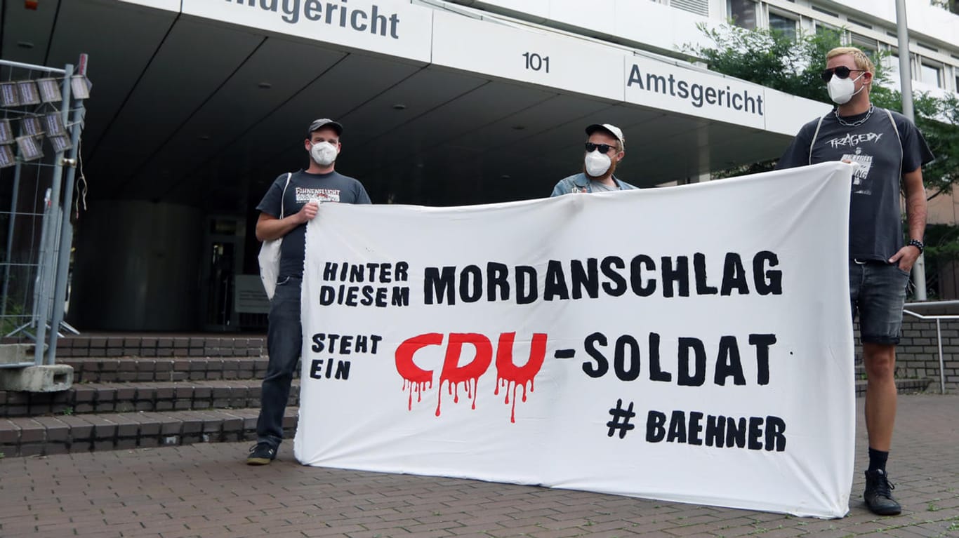 Drei Männer halten ein Banner vor dem Land-/Amtsgericht Köln bei einer Kundgebung zum Fall des ehemaligen Porzer CDU-Bezirksvertreters Hans-Josef Bähner: Der Prozess gegen den Politiker hat nach wie vor nicht begonnen.