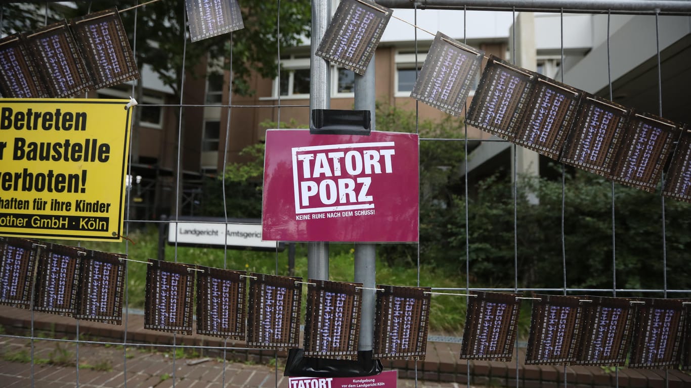 Das Bündnis "Tatort Porz" hat bei einer Kundgebung vor dem Land-/Amtsgericht Köln eine Postkartenaktion gegen Rassismus an einem Bauzaun platziert: "Bähner muss sich für seine Taten verantworten."
