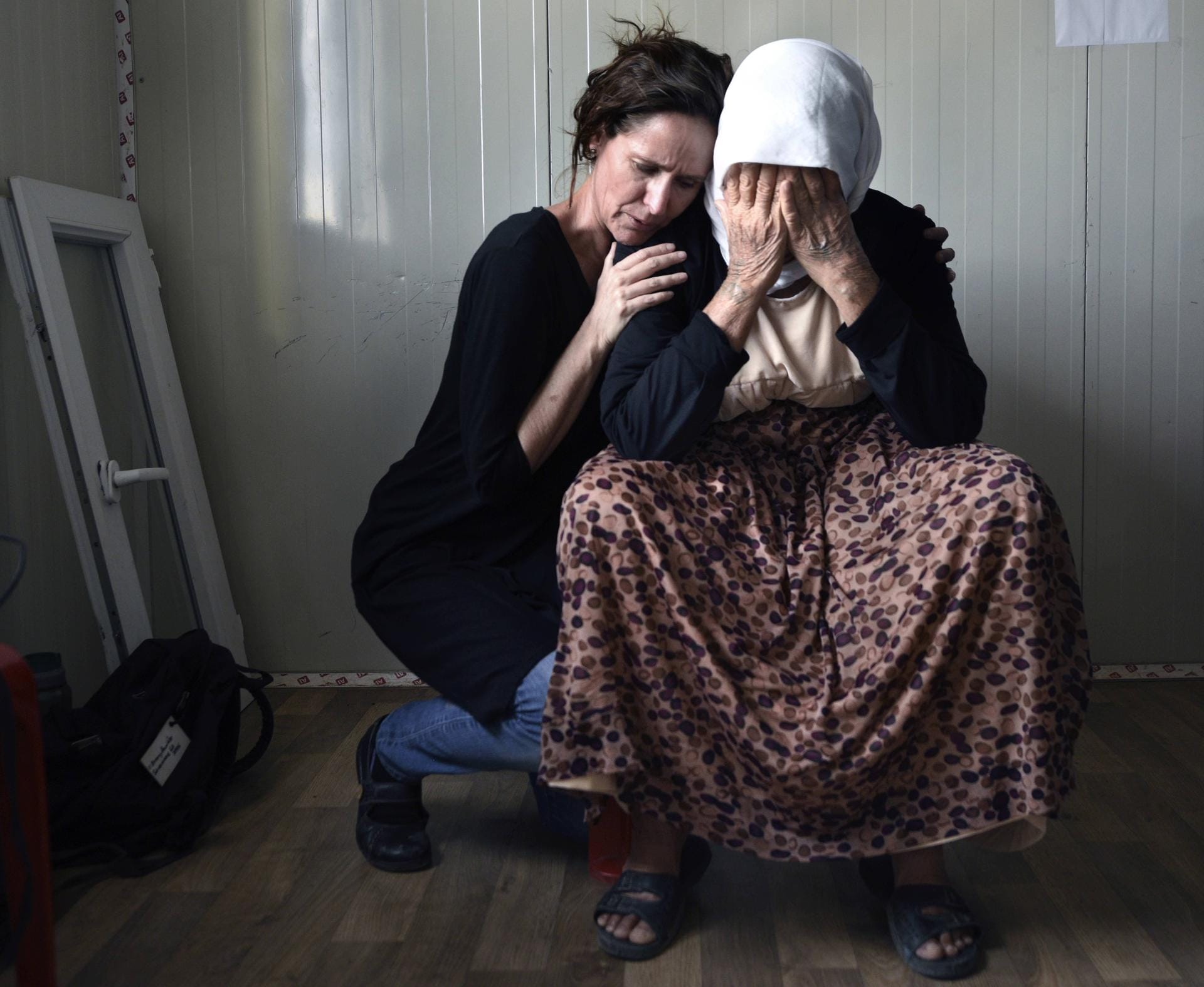 Eine 60-Jährige Frau weint in einem Flüchtlingslager um ihre von IS-Terroristen getöteten Kinder: Getröstet wird sie von einer Helferin einer internationalen Organisation.
