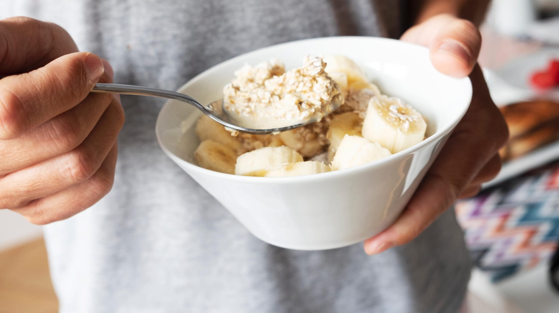 Ein Mann isst Haferbrei mit Bananen: Welches Essen der Magen bei Gastritis gut verträgt, ist individuell unterschiedlich.