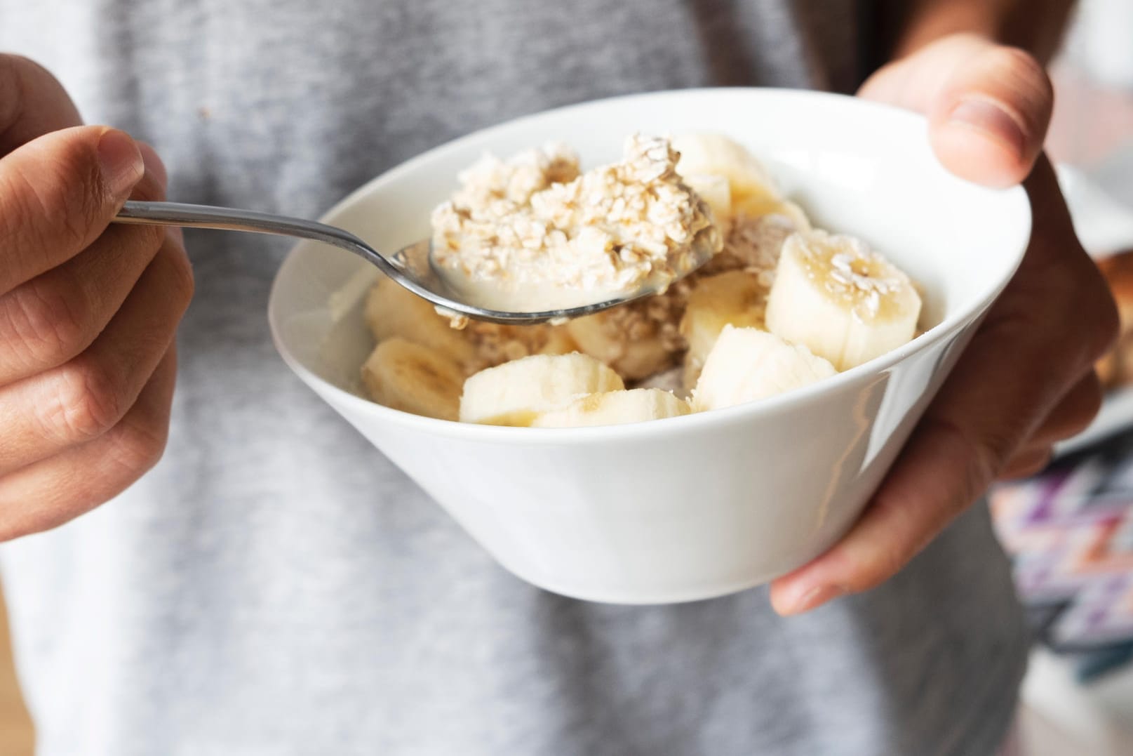 Ein Mann isst Haferbrei mit Bananen: Welches Essen der Magen bei Gastritis gut verträgt, ist individuell unterschiedlich.