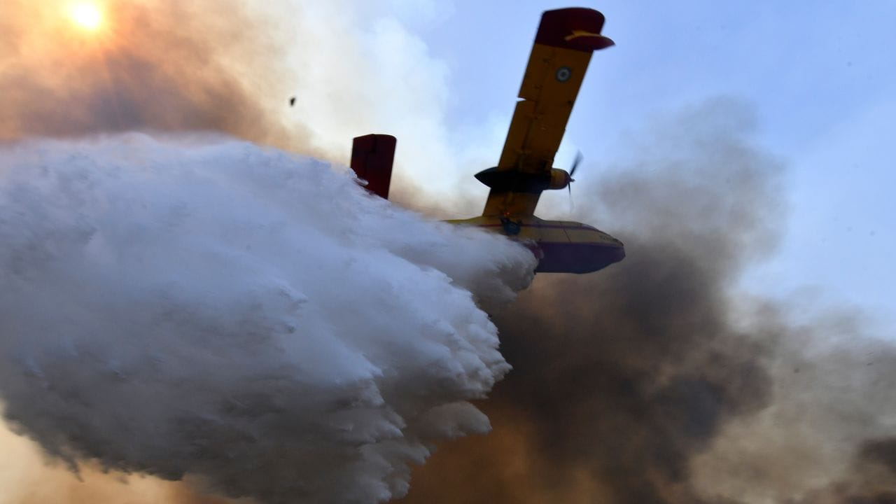Ein Flugzeug wirft Löschwasser über einem Waldbrand in Olympia ab.