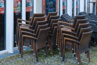 Stühle stehen vor einem geschlossenen Restaurant in Coesfeld (Archivbild). Wirtschaftsverbände warnen vor einem neuen Lockdown.