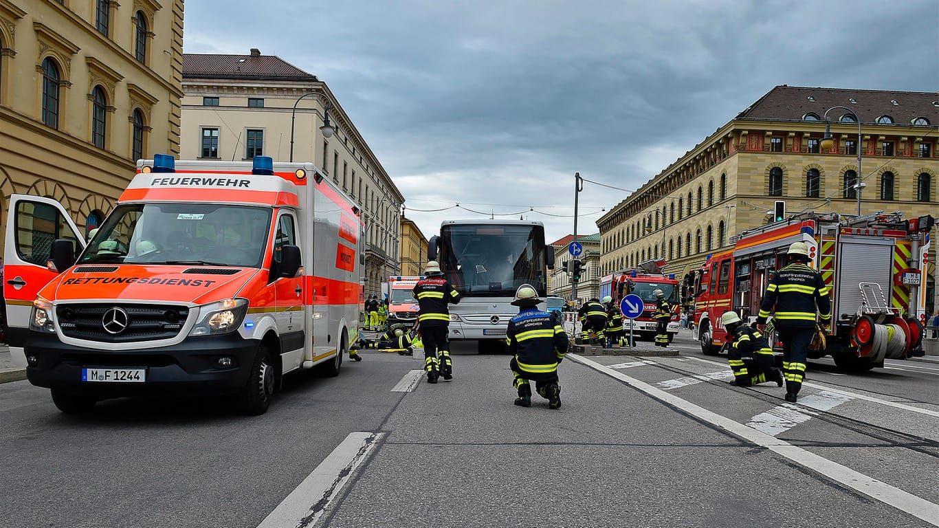 Die Feuerwehr im Einsatz an der Unfallstelle in der Münchner Maxvorstadt: Ein Mann war unter die Räder eines Busses geraten.