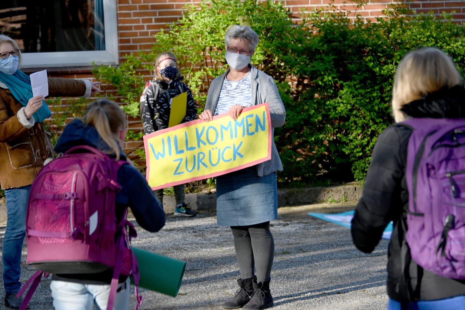 Mit einem Schild begrüßt eine Lehrerin Grundschulkinder zum Schulstart (Archivbild): Seit einer Woche sind in Schleswig-Holstein die Sommerferien vorbei.