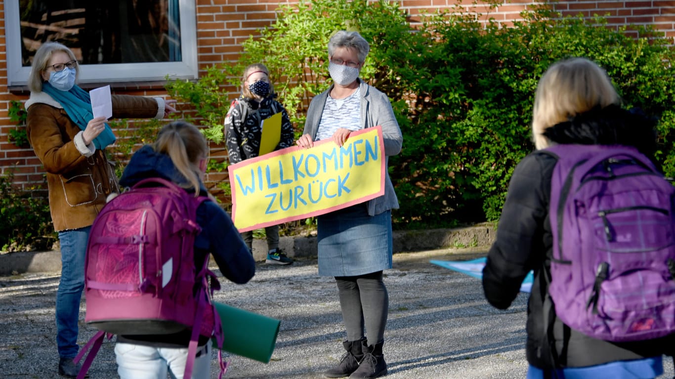 Mit einem Schild begrüßt eine Lehrerin Grundschulkinder zum Schulstart (Archivbild): Seit einer Woche sind in Schleswig-Holstein die Sommerferien vorbei.