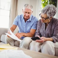 Älteres Paar sichtet Dokumente (Symbolbild): Wer eine Lebensversicherung kündigt, erhält den sogenannten Rückkaufswert.