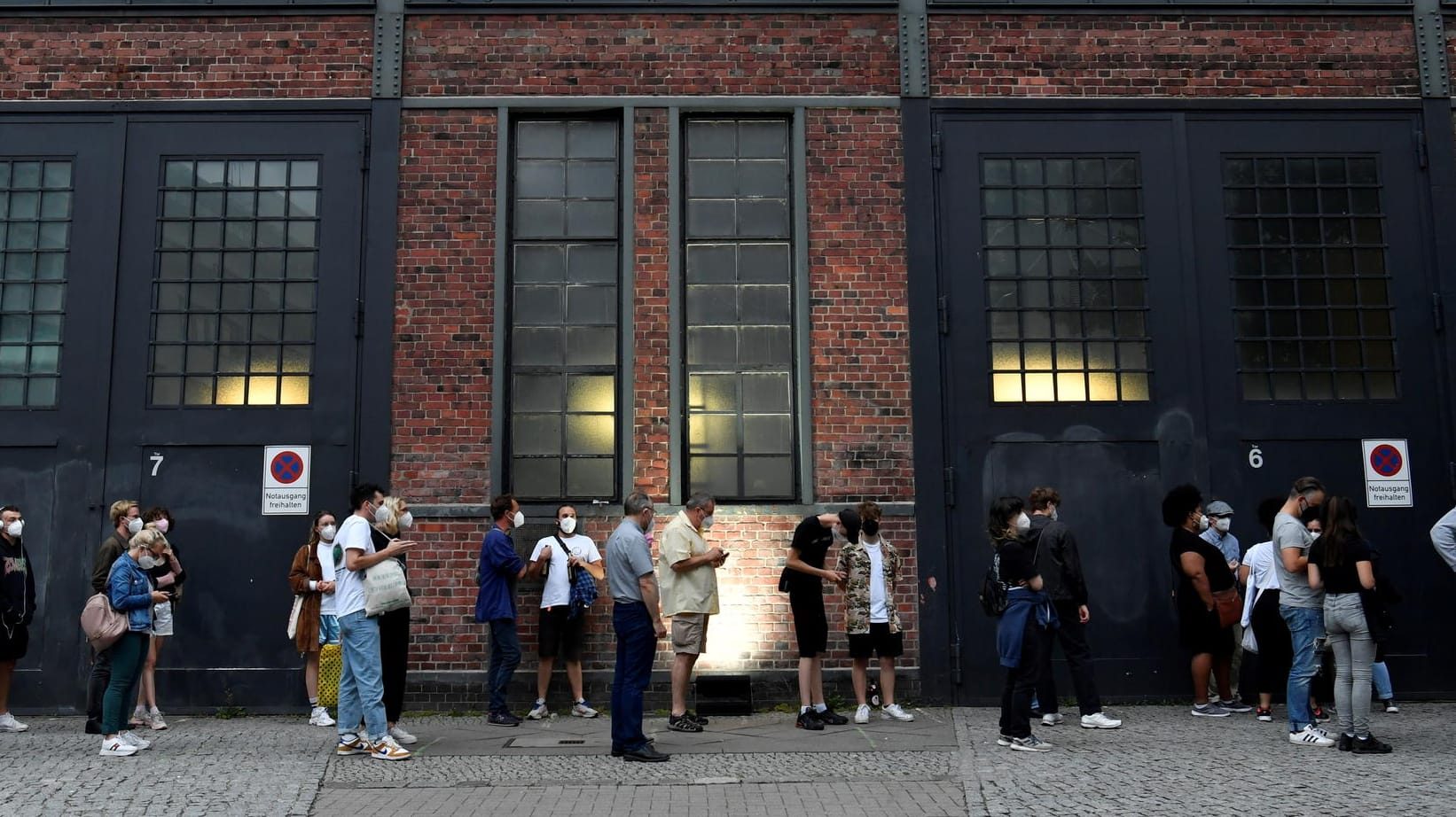 Menschen stehen vor einer Halle in einer Schlange: Sie warten nicht auf den Einlass in einen Club, sondern auf ihren Pieks im Impfzentrum Arena Berlin, wo bei der ersten "Langen Nacht des Impfens" großer Andrang herrschte.