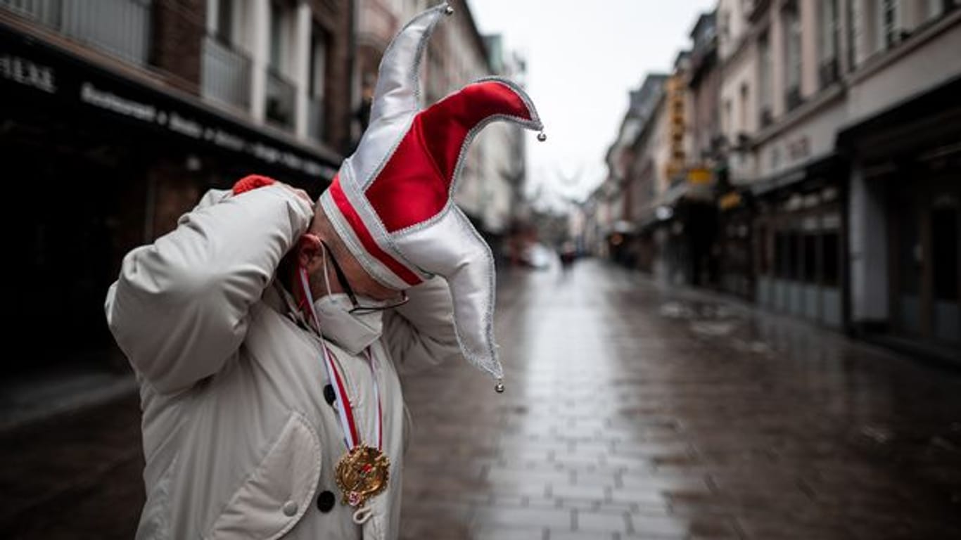 Ein Mann steht mit Karnevals-Mütze in einer Straße in der Düsseldorfer Altstadt (Archivbild): Ein negativer Corona-Test reiche nicht für den Schutz vor dem Virus.
