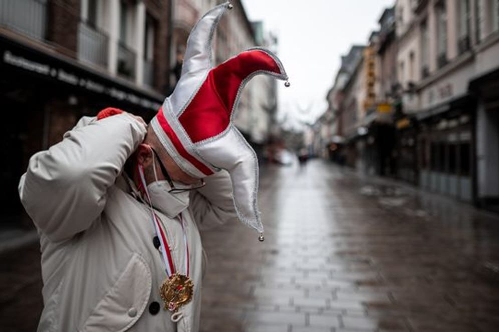 Ein Mann steht mit Karnevals-Mütze in einer Straße in der Düsseldorfer Altstadt (Archivbild): Ein negativer Corona-Test reiche nicht für den Schutz vor dem Virus.