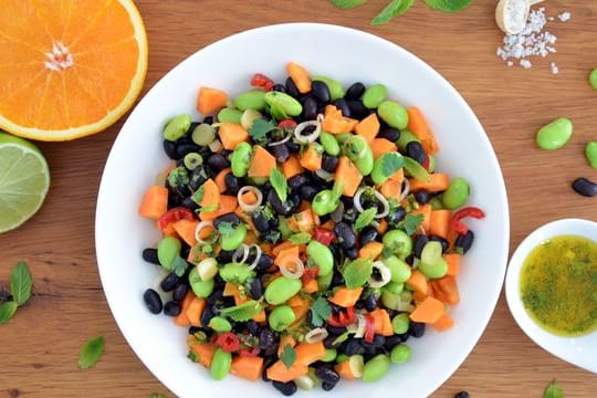 Leuchtend grüne Punkte vermischen sich mit dunklen und orangenen Farbtupfern: Zusammen mit dem Zitrusfrüchte-Dressing wird der nussig-würzige Bohnen-Mix zu einem frischen Salat.