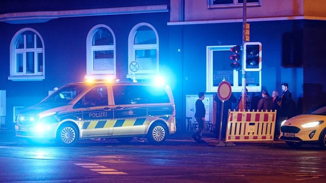 Ein Polizeiwagen steht mit Blaulicht an einer Straßensperre