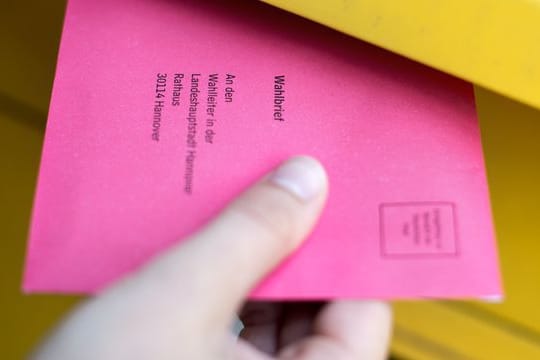 Eine Frau steckt einen Wahlbrief in einen Postkasten