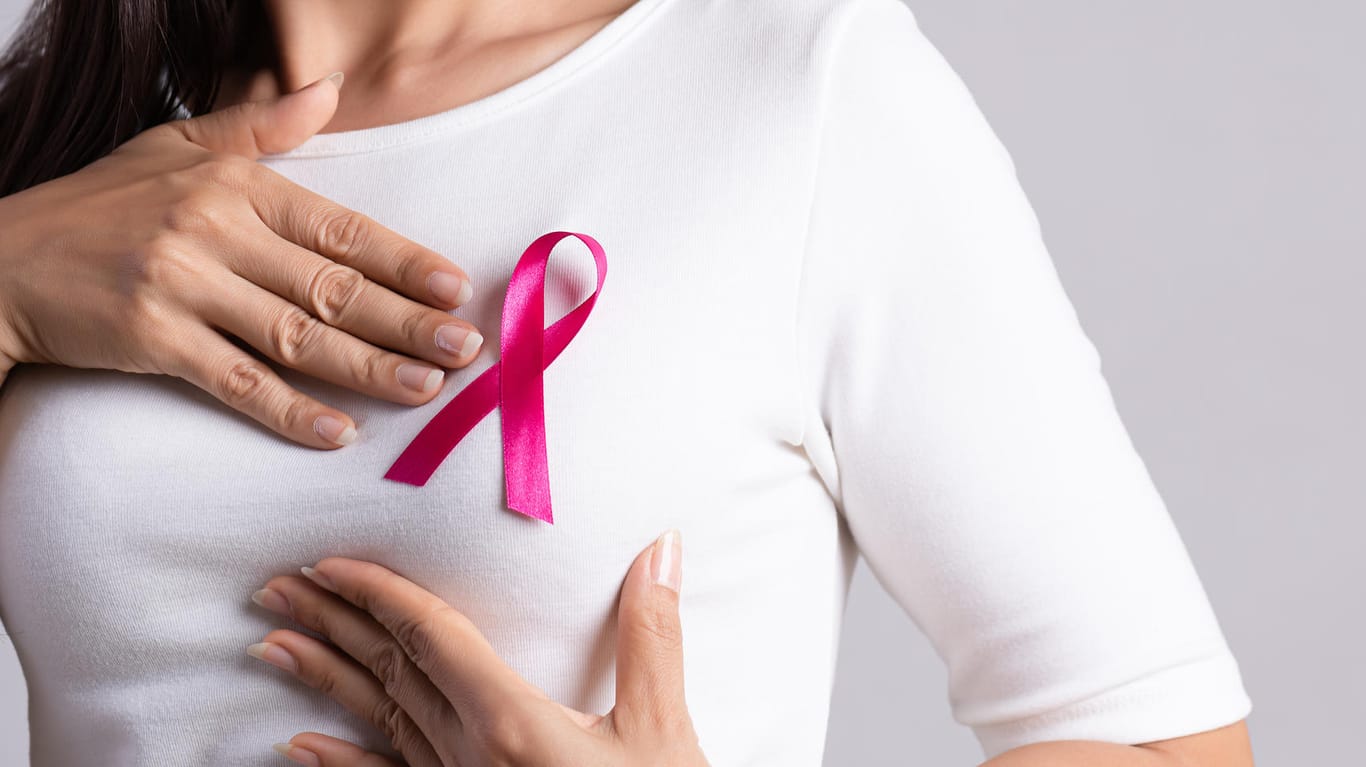 Eine Frau trägt eine rosa Schleife auf dem T-Shirt. Sie steht symbolisch für Solidarität mit Brustkrebspatientinnen.