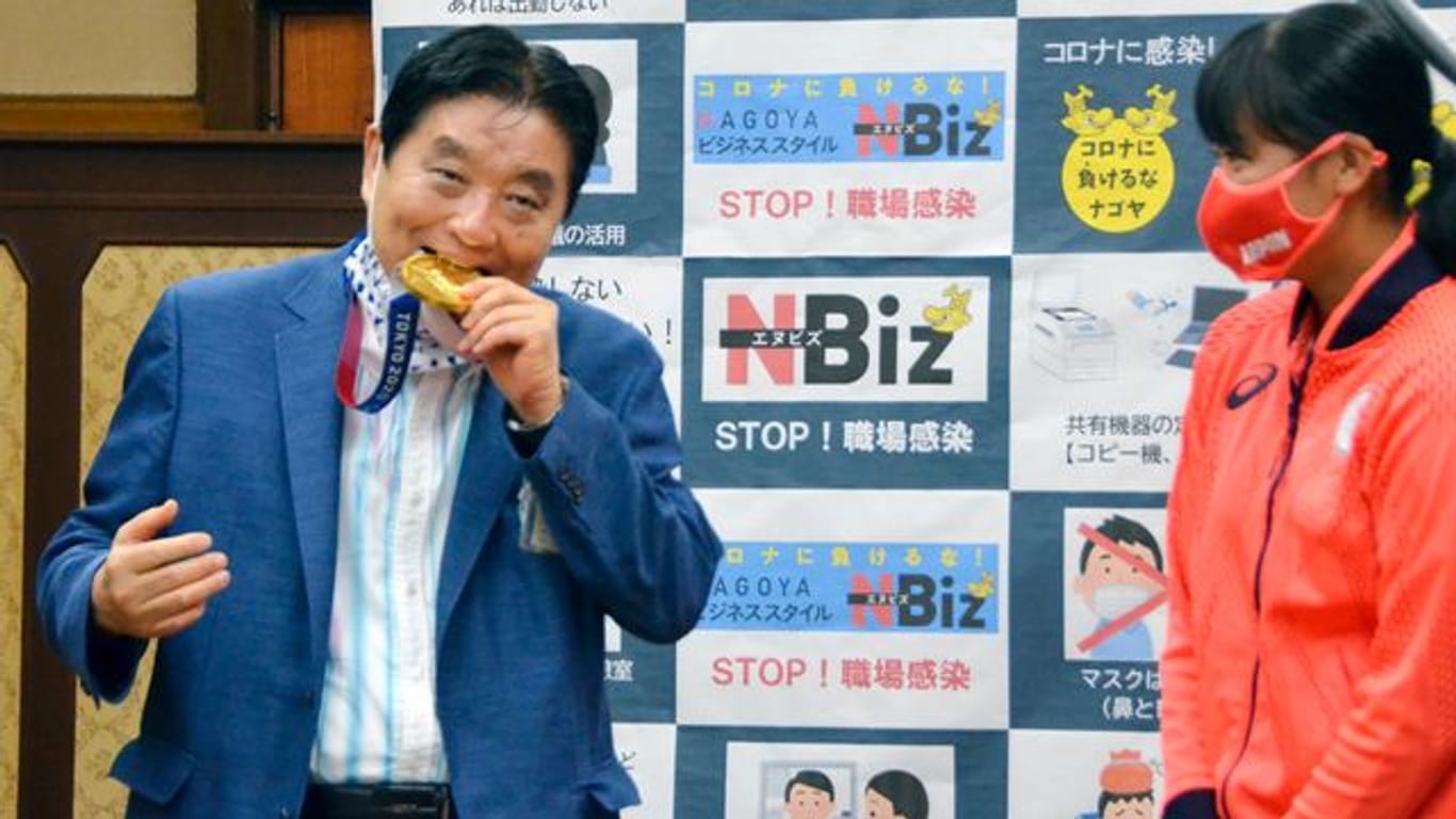 Nagoyas Bürgermeister Takashi Kawamura (l) biss in die Gold-Medaille von Miu Goto.