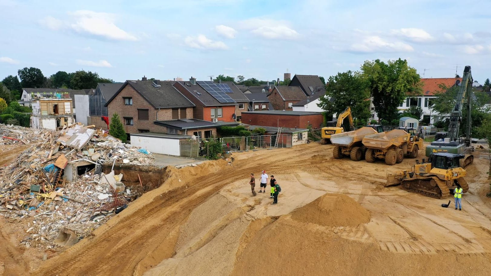 Helfer stehen neben Baugeräten auf einem Hügel an der Abbruchkante: Wie lange der Wiederaufbau dauern wird, ist noch unklar.