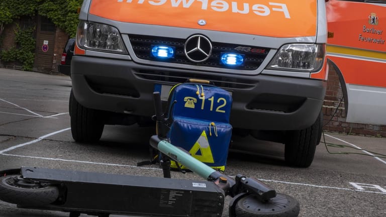 Ein E-Scooter liegt vor einem Rettungswagen (Symbolbild): Der Fahrer wurde schwer verletzt.