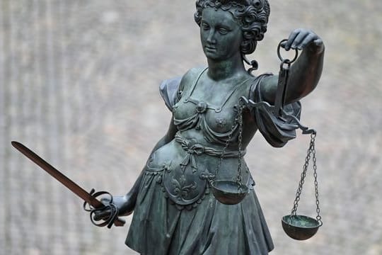 Eine Statue der Justitia hält eine Waage in der Hand