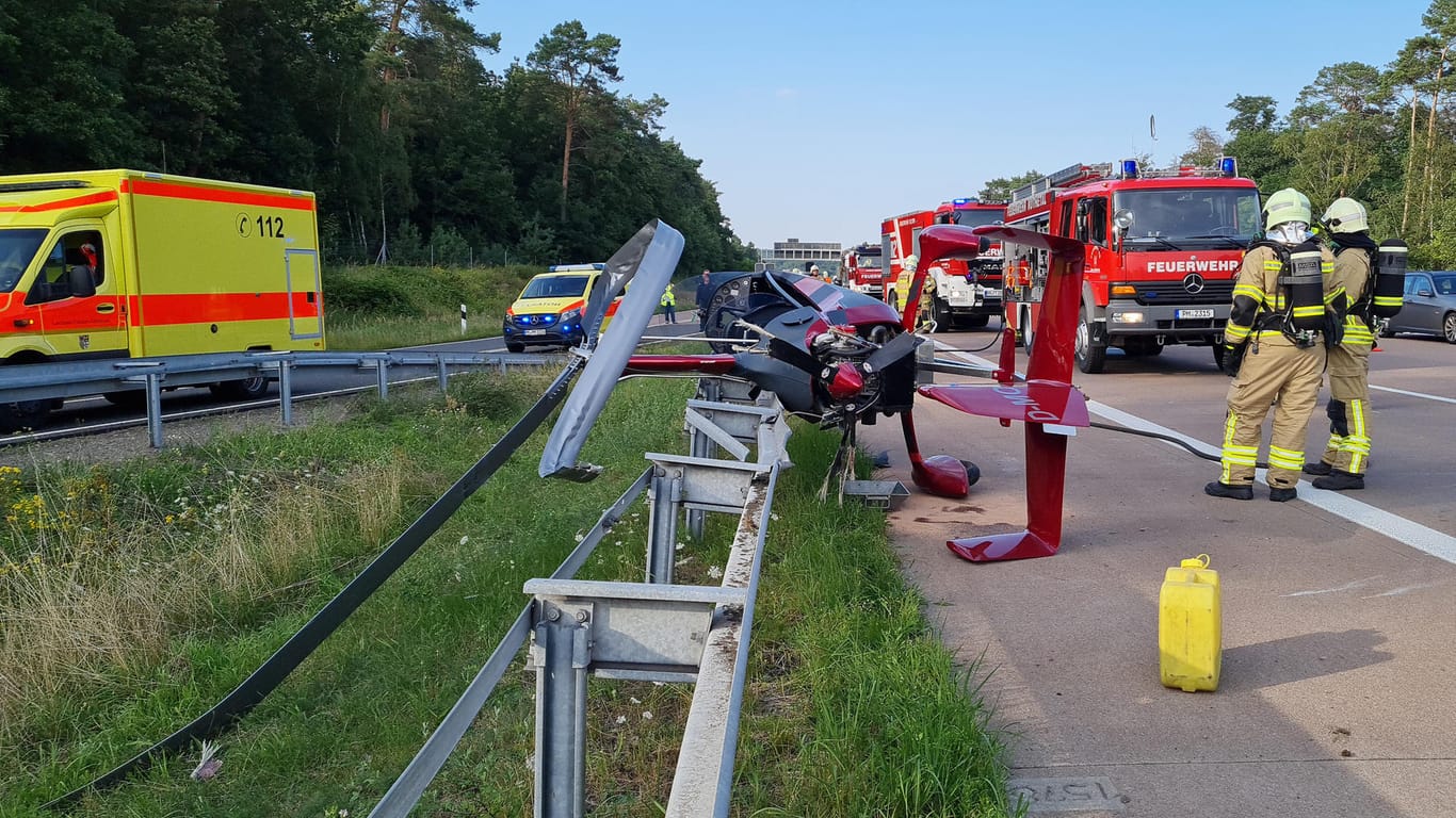 Brandenburg, Michendorf: Einsatzkräfte der Feuerwehr stehen an der Absturzstelle eines Hubschraubers am Autobahndreieck Nuthetal.