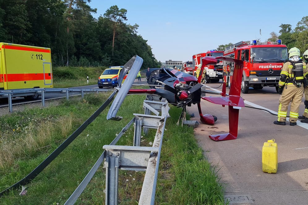 Brandenburg, Michendorf: Einsatzkräfte der Feuerwehr stehen an der Absturzstelle eines Hubschraubers am Autobahndreieck Nuthetal.