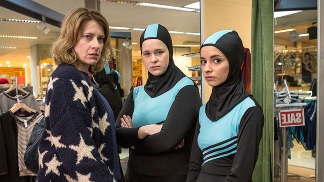 Wanda (Caroline Peters) kauft für ihre Tochter Nina (Chantal Zitzenbacher, M) und deren beste Freundin Maryam (Duygu Arslan) einen Burkini.