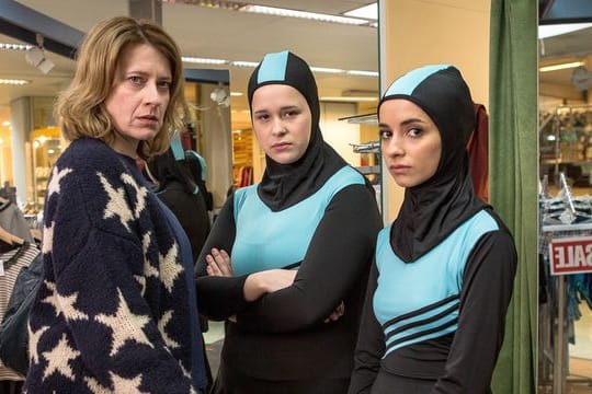 Wanda (Caroline Peters) kauft für ihre Tochter Nina (Chantal Zitzenbacher, M) und deren beste Freundin Maryam (Duygu Arslan) einen Burkini.