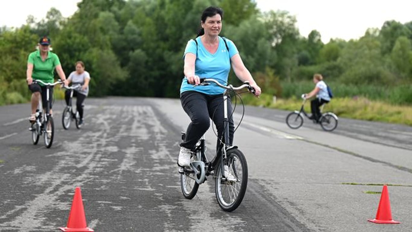 Sicherer radeln: Monika Kraus (vorn) aus Marburg nimmt an einem Radfahrkurs auf dem Alten Flugplatz im Stadtteil Bonames teil. Die Kurse wenden sich gleichermaßen an Anfänger, Wiedereinsteiger und an unsichere Radfahrerinnen und Radfahrer.