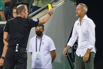 Adi Hütter (r.) sieht die Gelbe Karte von Schiedsrichter Marco Fritz: Der Gladbacher Trainer war mit den Elfmeter-Entscheidungen unzufrieden.