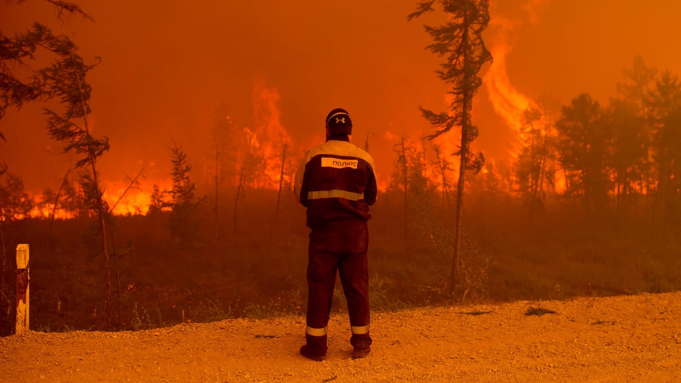 Ein Feuerwehrmann steht am Rand eines Waldbrands westlich von Jakutsk. Die Waldbrandsituation in Russland nimmt immer dramatischere Ausmaße an.