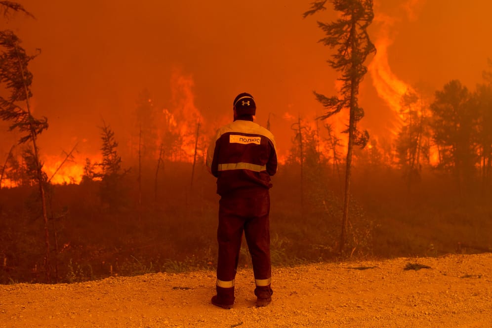 Ein Feuerwehrmann steht am Rand eines Waldbrands westlich von Jakutsk. Die Waldbrandsituation in Russland nimmt immer dramatischere Ausmaße an.