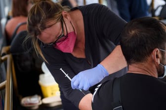 Eine Impfung in einem Impfbus vor dem Kieler Stadion (Foto): Eine Mitarbeiterin des Deutschen Roten Kreuzes impft Bürger in einer mobilen Impfstation.