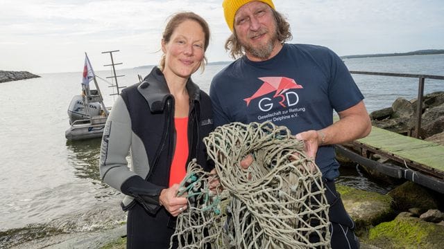 Das Schauspieler-Paar Tessa Mittelstaedt (47) und Matthias Komm (54) steht vor einem Tauchgang in die Ostsee vor der Insel Rügen an der Tauchbasis Mukran mit einem Netz in der Hand da.