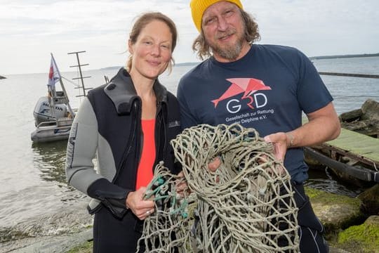 Das Schauspieler-Paar Tessa Mittelstaedt (47) und Matthias Komm (54) steht vor einem Tauchgang in die Ostsee vor der Insel Rügen an der Tauchbasis Mukran mit einem Netz in der Hand da.