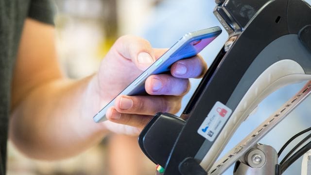 Ein Smartphone wird an ein Kassenterminal gehalten. Ein Smartphone wird an ein Kassenterminal gehalten.