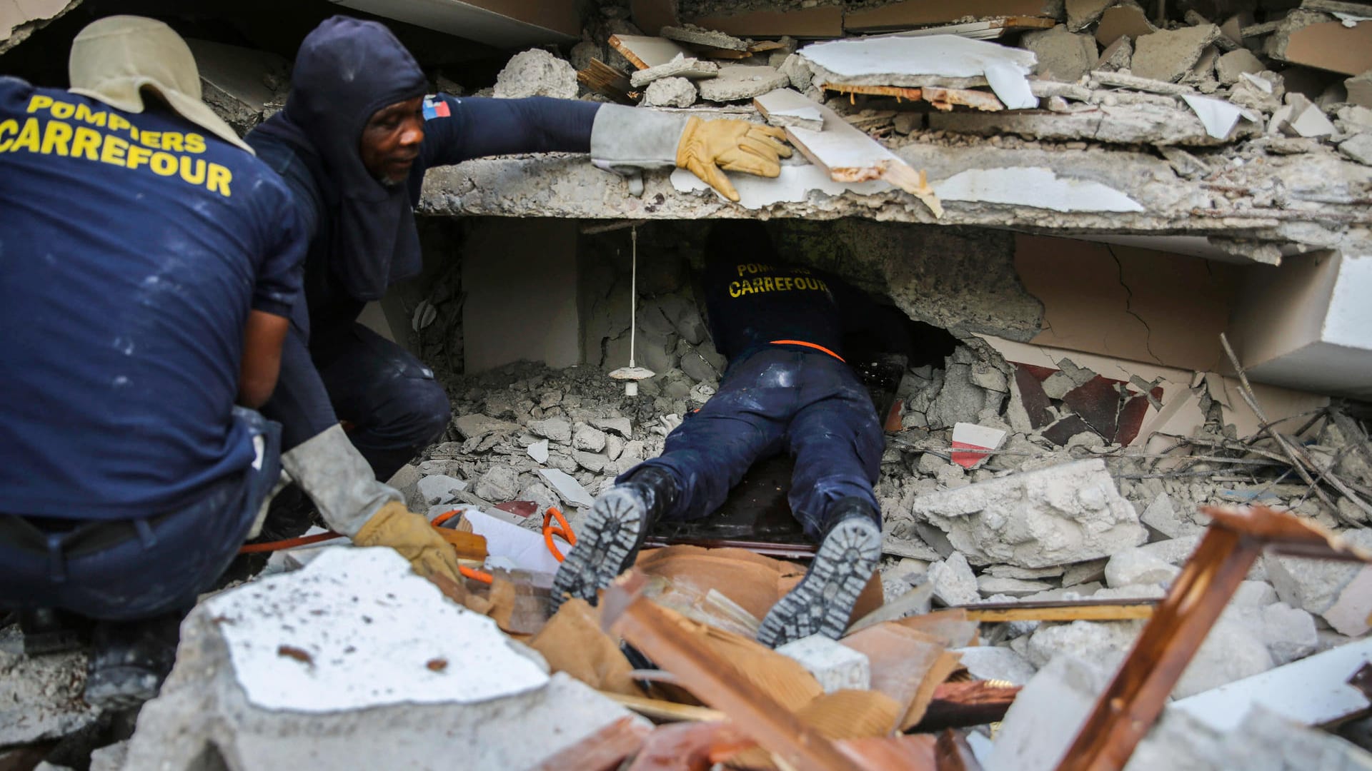 Feuerwehrleute suchen zwischen den Trümmern eines Hauses auf Haiti nach Überlebenden.