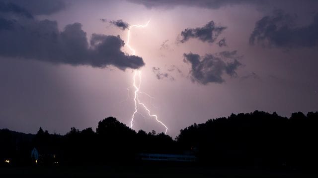 Ein Blitz erhellt den Nachthimmel (Symbolbild): Bis zur Wochenmitte sollen sich die Gewitter wieder verziehen.