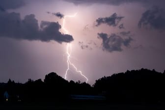 Ein Blitz erhellt den Nachthimmel (Symbolbild): Bis zur Wochenmitte sollen sich die Gewitter wieder verziehen.