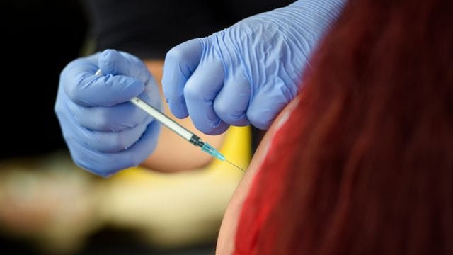 Eine Mitarbeiterin des Deutschen Roten Kreuzes impft eine Frau Eine Mitarbeiterin des Deutschen Roten Kreuzes impft eine Frau