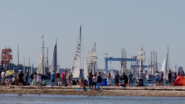 Zuschauer verfolgen vom Strand aus die Windjammerparade zur Kieler Woche (Archivbild): Die KiWo findet in kleinerem Rahmen statt.